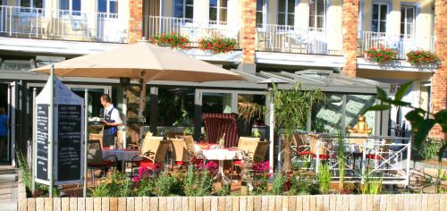 a restaurant with an umbrella and tables and chairs at Vineta Strandhotels in Zinnowitz