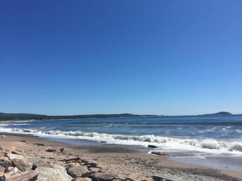 a beach with rocks and the ocean on a sunny day at Lantern Hill & Hollow in Ingonish Beach