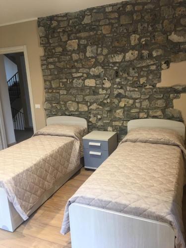 two beds in a room with a stone wall at Residence La Canonica in Costa Valle Imagna