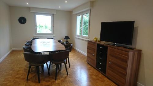 a dining room with a table and a flat screen tv at La maison de Paul in Mittelwihr