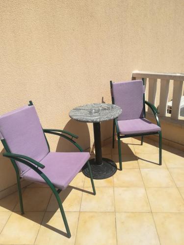two chairs and a table with a table and purple chairs at Apartments Ivanka in Ston