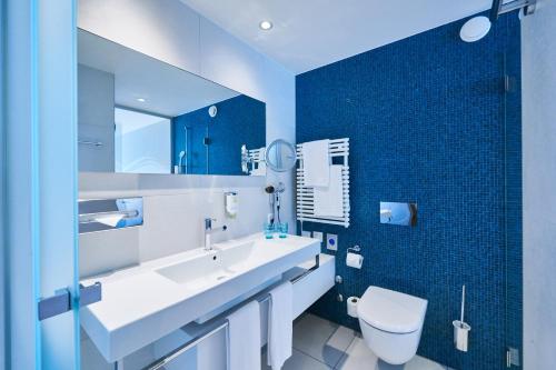 a bathroom with a white sink and a toilet at Hotel Holiday Thun in Thun