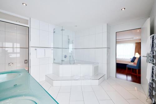 a white bathroom with a tub and a shower at Hotel Holiday Thun in Thun