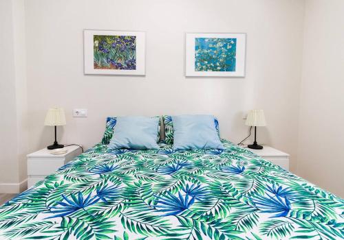 um quarto com uma cama com um cobertor azul e verde em Victoria - Apartamento Playa em Cádiz