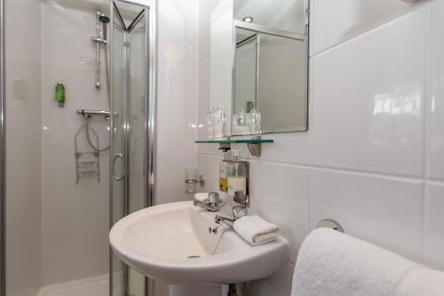a white bathroom with a sink and a shower at Clifton Villa Guest House in Llandudno