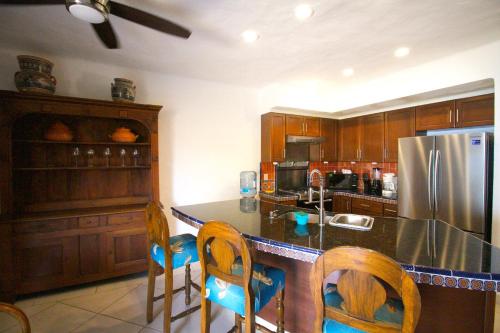 a kitchen with a counter with chairs and a refrigerator at Villas del Sol en Los Tules in Puerto Vallarta