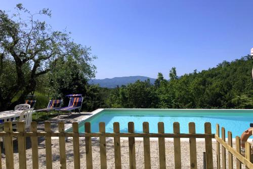 a swimming pool with a wooden fence and chairs at Podere Badia Valdrago Agriturismo Mugello Circuit in Scarperia