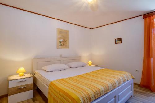 a small bedroom with a bed with a yellow blanket at CASA OLIVA in Sveti Jakov