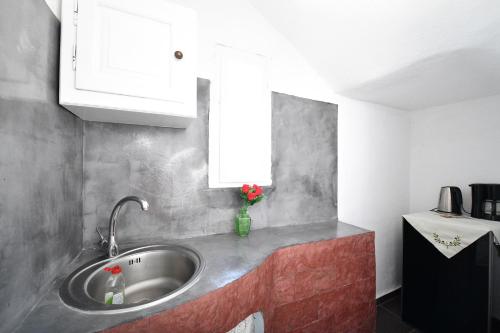 a kitchen sink with a vase of flowers on the counter at Santo Margarita in Oia