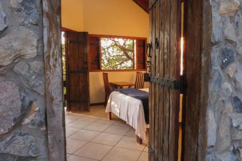 a room with a bed and a window and a table at Chalé do Bosque in Bonito
