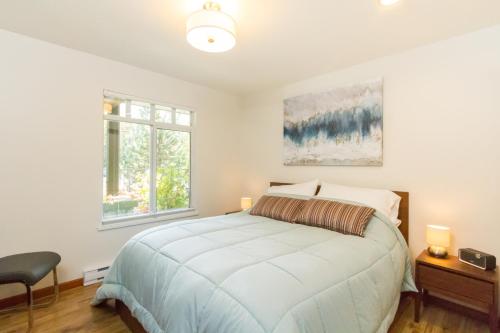 a white bedroom with a bed and two windows at 63 Lagoons in Whistler