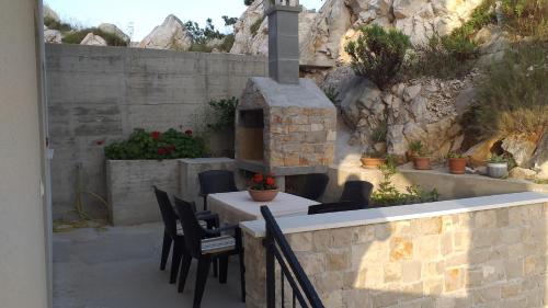 a patio with a table and chairs and a brick oven at Apartman Zaklopatica in Lastovo