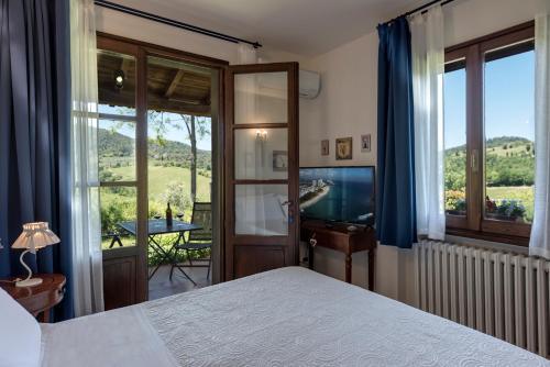 Un dormitorio con una cama y un televisor y un balcón. en Villa Del Sole, en San Gimignano