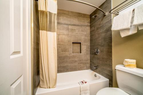 a bathroom with a white tub and a toilet at Regency Inn & Suites Downey in Downey