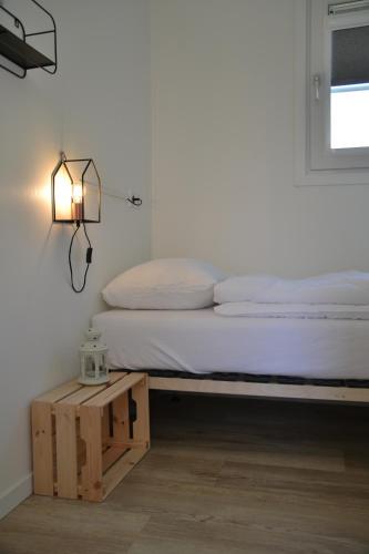 ドンブルグにあるMinicamping Shalomのランプとテーブルが備わる部屋のベッド1台分です。