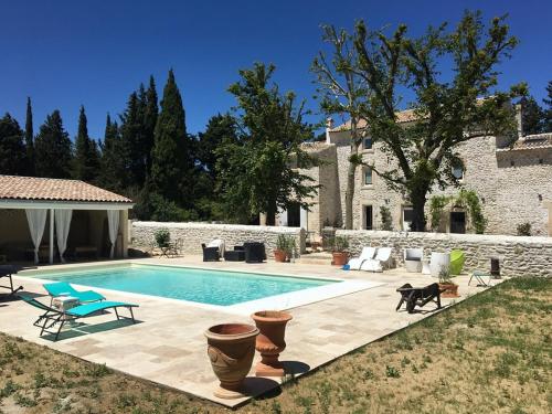 - une piscine en face d'une maison en pierre dans l'établissement gite le cabanon, à Réauville
