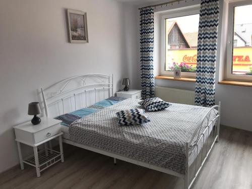 a bedroom with a white bed and two windows at Pokoje Gościnne PLUS in Ustka