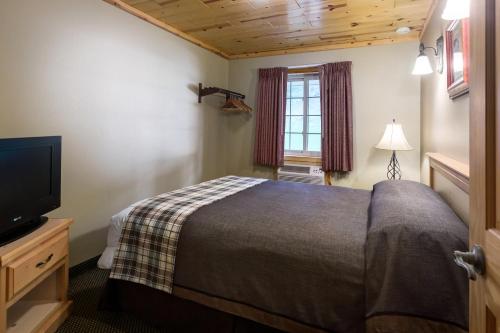 a bedroom with a bed and a flat screen tv at Rock Crest Lodge & Cabins in Custer