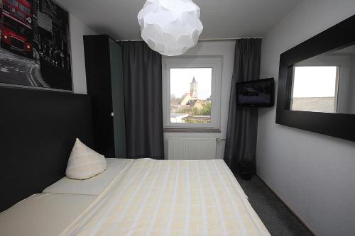 a bedroom with a bed and a window and a chandelier at SL'otel Budget in Bernburg