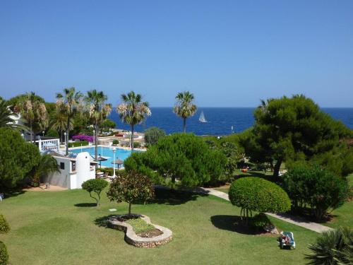 a view of a resort with a swimming pool and the ocean at Apartamentos Parque Mar in Cala d´Or