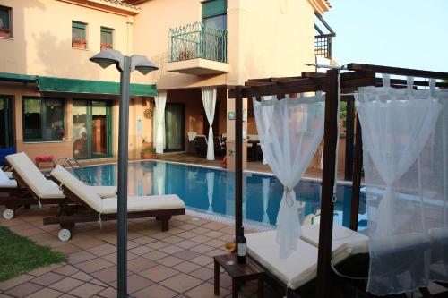 ein Haus mit einem Pool und einigen Stühlen und einem Baldachin in der Unterkunft 4-seasons pool villa near Meteora in Tríkala
