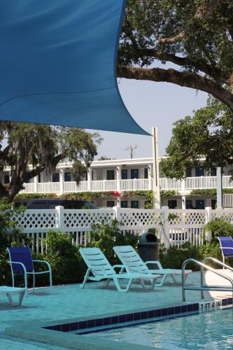 a pool with lounge chairs next to a white fence at Southern Oaks Inn - Saint Augustine in Saint Augustine
