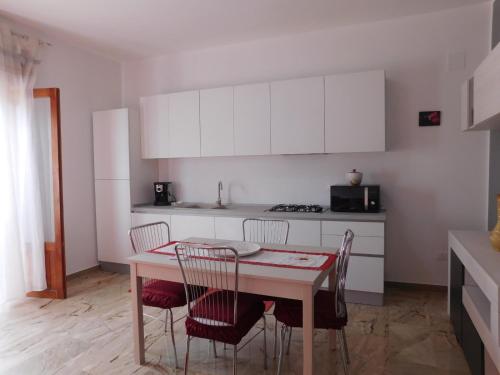 kuchnia ze stołem, krzesłami i białymi szafkami w obiekcie SOPHIA Appartament w mieście Trappeto