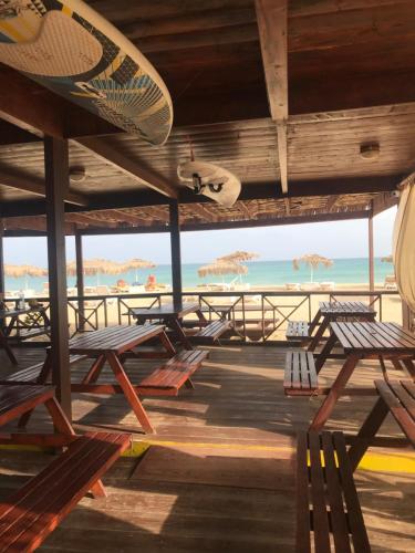 a deck with chairs and a surfboard on the beach at Blue Eagle Guesthouse - Casa de hospedes in Santa Maria