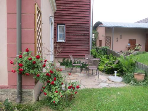 a patio with a table and chairs and red flowers at Romantik-Villa LebensART in Reichenfels