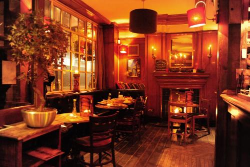 a restaurant with tables and chairs and a fireplace at Prince Arthur in London
