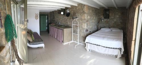 a bedroom with a bed in a stone wall at Scorpio house 180 sea view - Serifians Residences in Serifos Chora