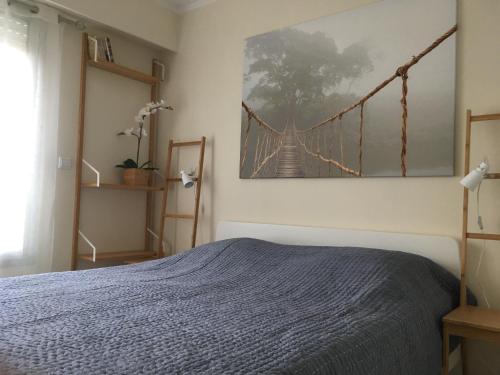 a bedroom with a bed and a picture of a suspension bridge at Quiet flat next to the beach in Nice
