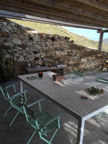 a picnic table and two chairs in front of a stone wall at Scorpio house 180 sea view - Serifians Residences in Serifos Chora