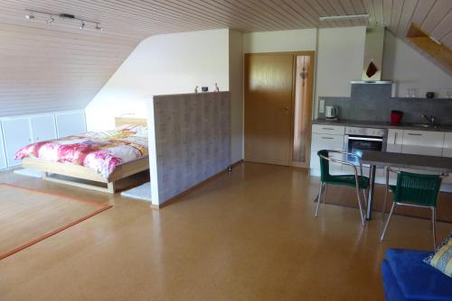 ein Schlafzimmer mit einem Bett und einem Tisch sowie eine Küche in der Unterkunft Enzkreisspitze in Neuenbürg