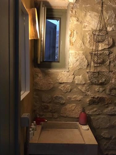 a bathroom with a stone wall and a window at Scorpio house 180 sea view - Serifians Residences in Serifos Chora