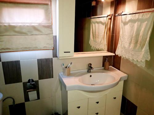 a bathroom with a white sink and a window at Handmade peaceful cozy house near the beach in Nea Kalikratia