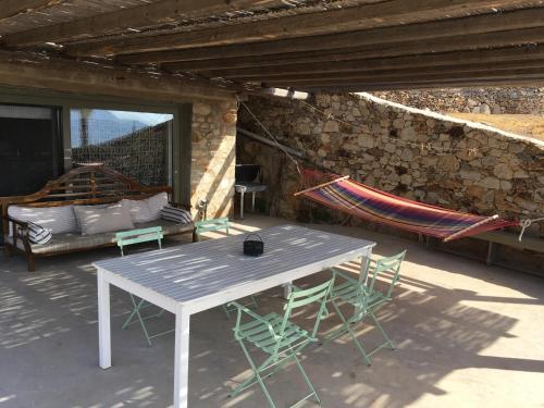 a patio with a table and chairs and a hammock at Scorpio house 180 sea view - Serifians Residences in Serifos Chora
