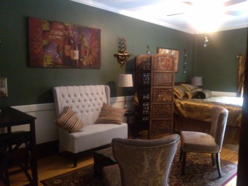 a living room with a white chair and a bed at Firehouse Inn in Barre