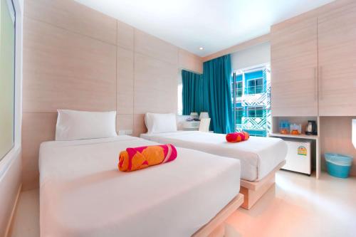 a hotel room with two beds with red and yellow pillows at Mirage Express Patong Phuket Hotel in Patong Beach