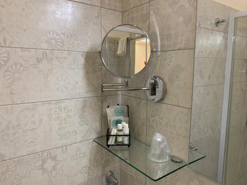 a bathroom with a glass shelf and a mirror at B&B In Centro in Crotone