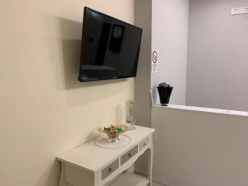 a tv hanging on a wall with a white table at B&B In Centro in Crotone