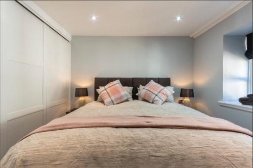 a bedroom with a large bed with two pillows at Denbrae Cottage West in St. Andrews