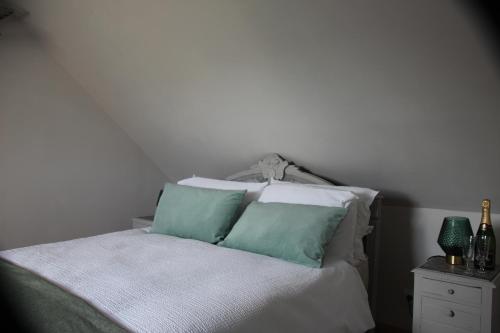 a bed with green and white pillows on it at Belle Vue Terrasse in Giverny