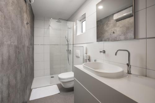 a white bathroom with a sink and a toilet at Holiday Homes Kanajt in Punat