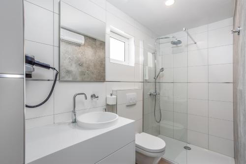 a white bathroom with a sink and a toilet at Holiday Homes Kanajt in Punat