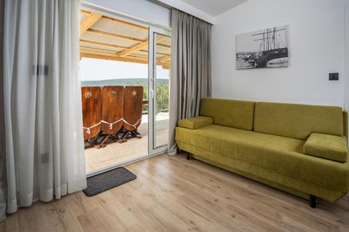 a living room with a green couch and a sliding glass door at Holiday Homes Kanajt in Punat