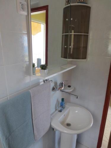a white bathroom with a sink and a mirror at APARTMAN RITA in Pag
