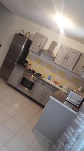 une cuisine avec des armoires blanches et un four à plaques de cuisson dans l'établissement Gîte O'Cigales, à Sablet