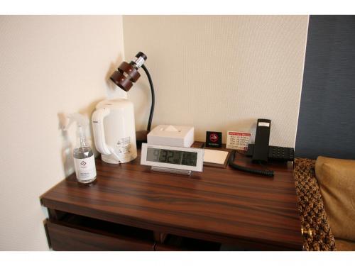 a table with a coffee maker and a clock on it at One's Hotel Fukuoka in Fukuoka