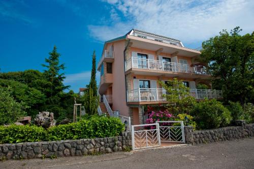 uma casa cor-de-rosa com uma vedação à frente. em Apartments and Rooms Njivice em Njivice